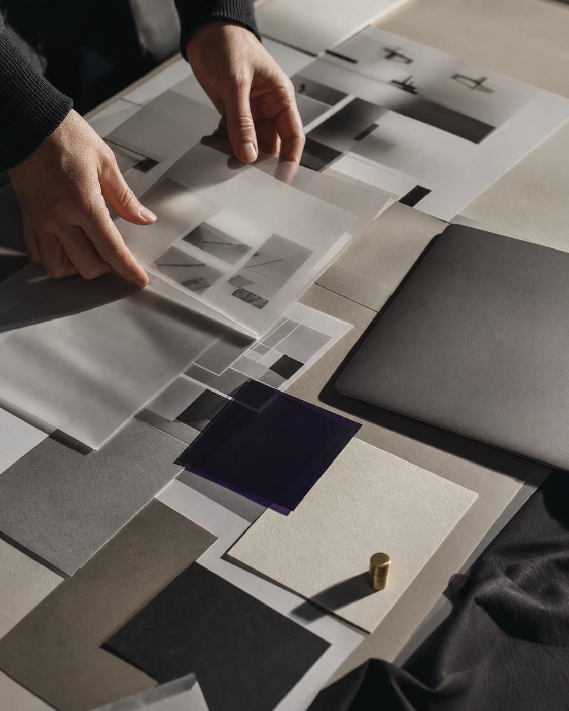 Manos organizando pruebas de diseño y materiales en una mesa de trabajo